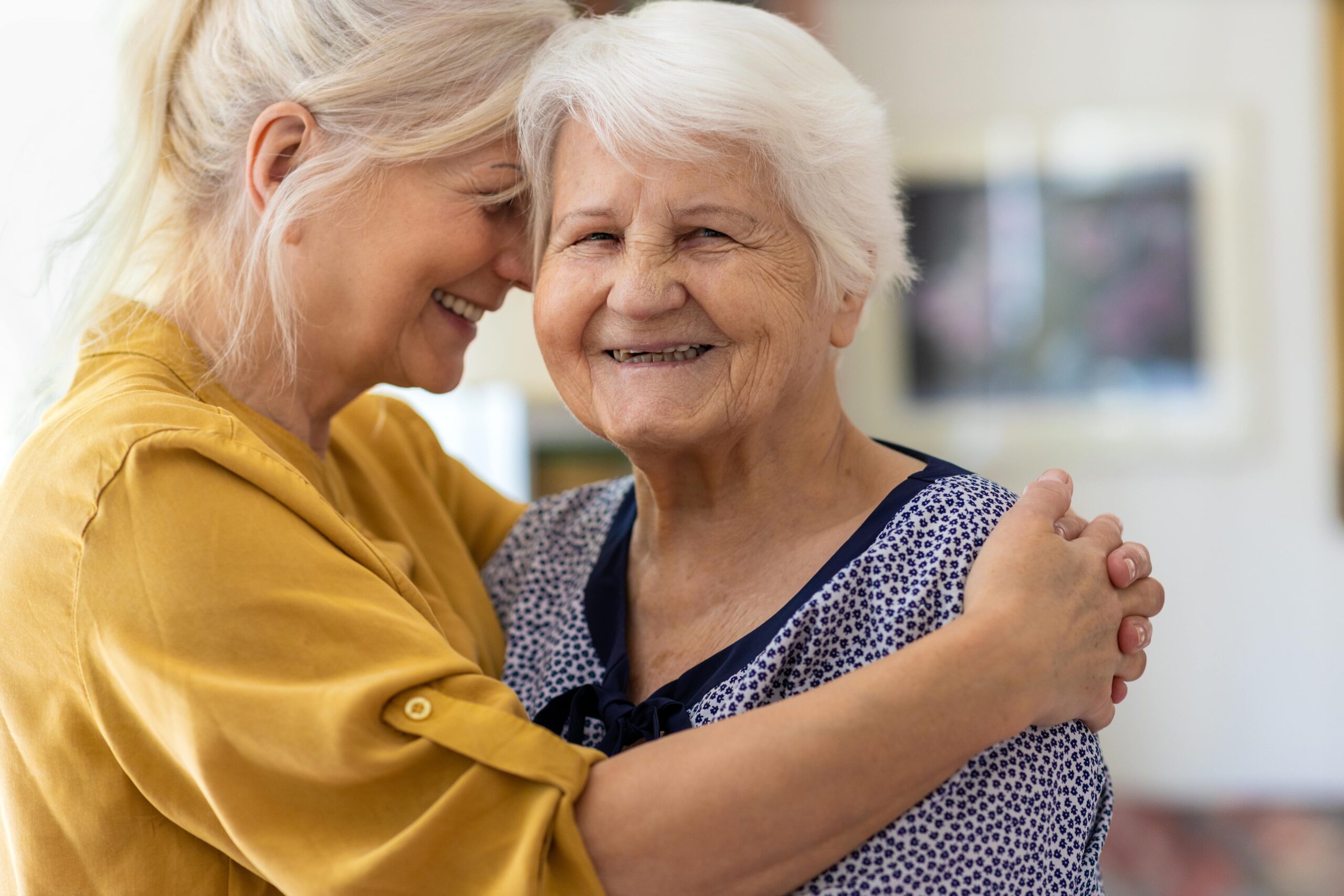 woman hugging a smiling elderly woman